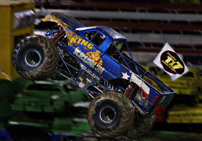 Monster truck carrying the TX7 logo crushing a car